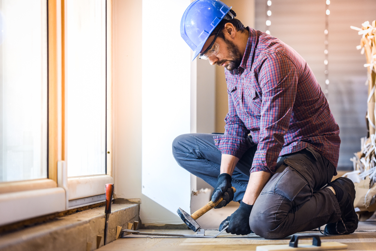 Carpenter installing hardwood floor. Home Living Construction ensures complete restoration of your home after fire damage.