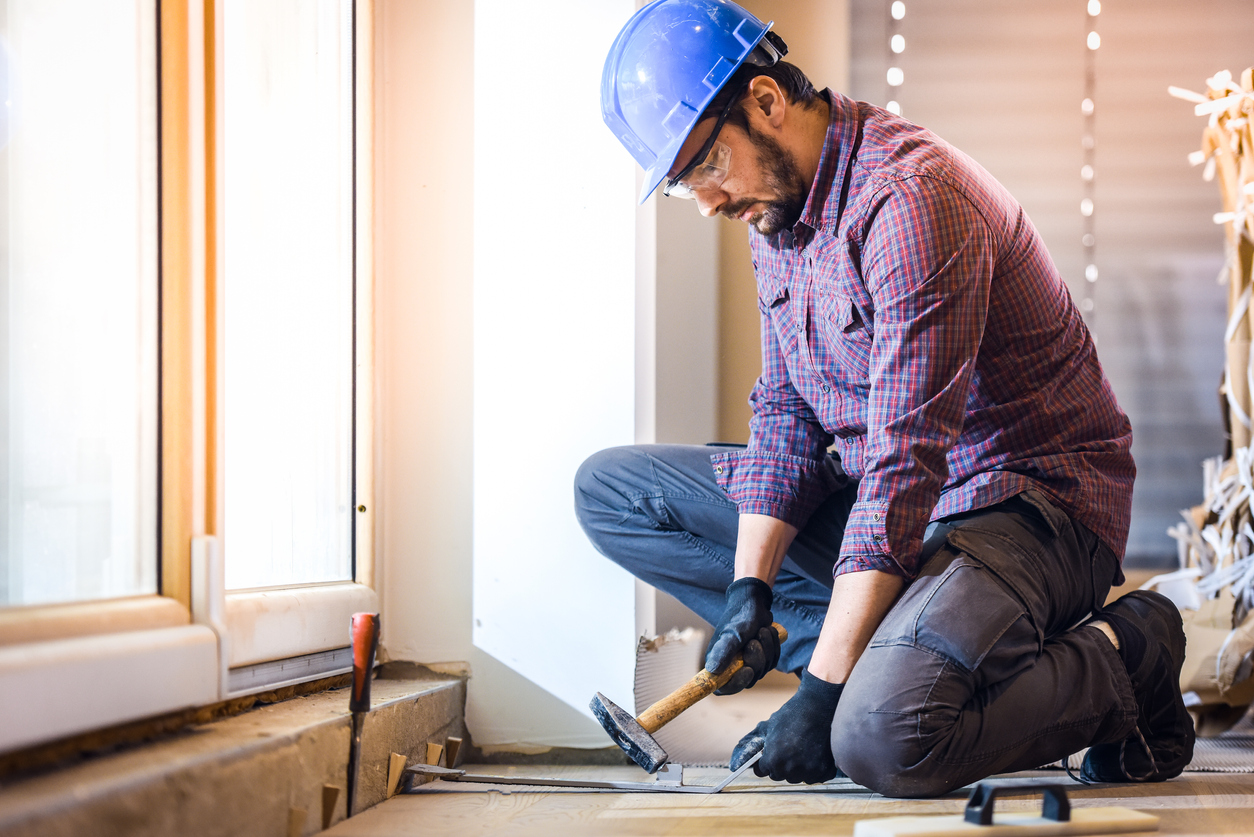 Carpenter installing hardwood floor Carpenter installing hardwood floor. Home Living Construction ensures complete restoration of your home after fire damage.