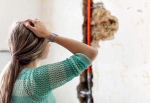 Woman looking at damage after a water pipe leak at home. We provide emergency services when this type of thing happens.