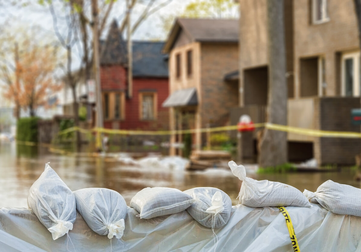 Close shot of flood Protection Sandbags with flooded homes in the background